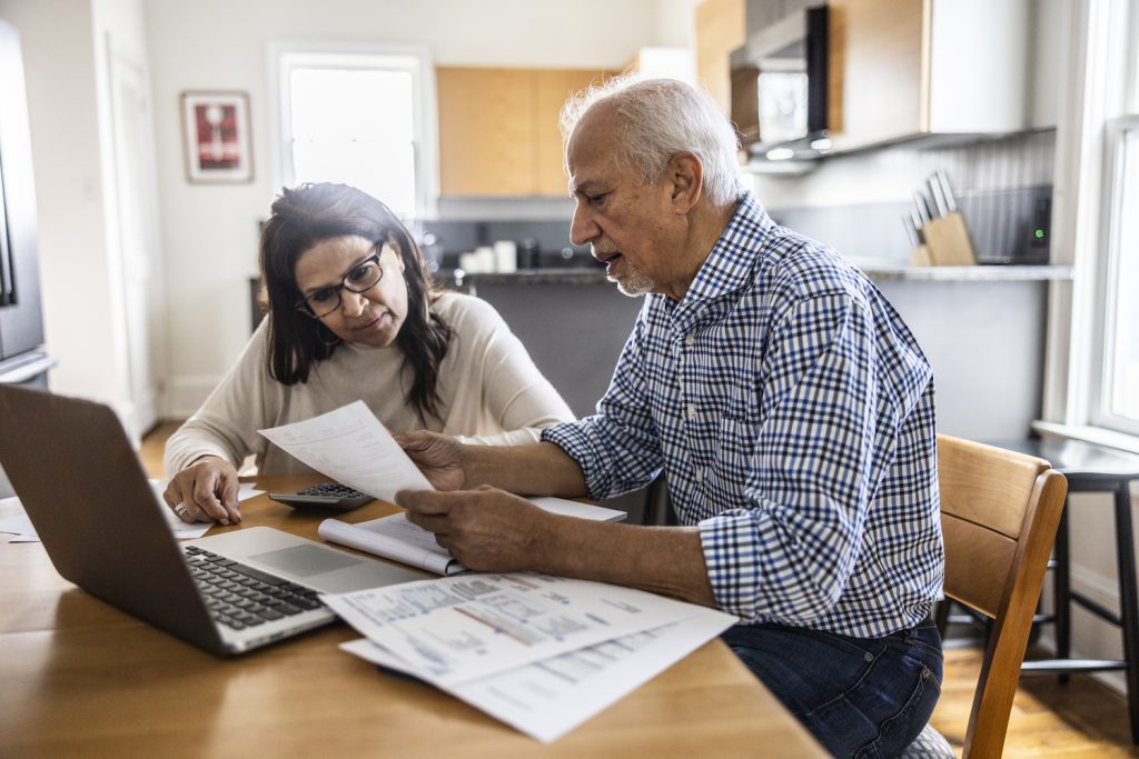 Senior couple paying bills at kitchen table